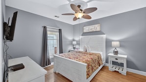 A bedroom with a bed, a ceiling fan, a desk, a lamp, and a window with curtains. - Magnolia North 4843-103 (Myrtle Beach)