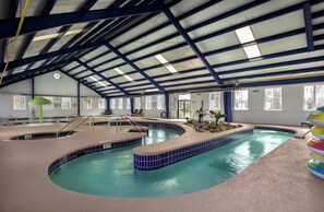 An indoor swimming pool with a curved design, multiple lanes, and a tiled edge. - Magnolia Place 4757-104 (Myrtle Beach)