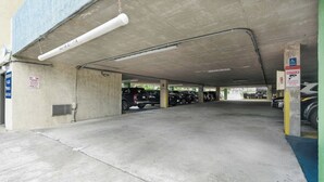 An underground parking garage with concrete pillars, fluorescent lighting, and a blue handicap parking sign. - Meridian Plaza 1401 (Myrtle Beach)