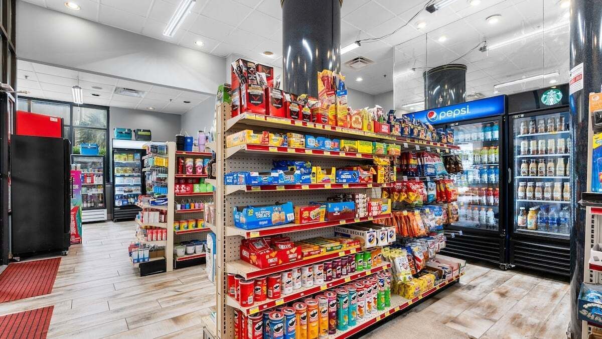 Una tienda de comestibles con estantes llenos de bocadillos, bebidas y productos para el hogar.