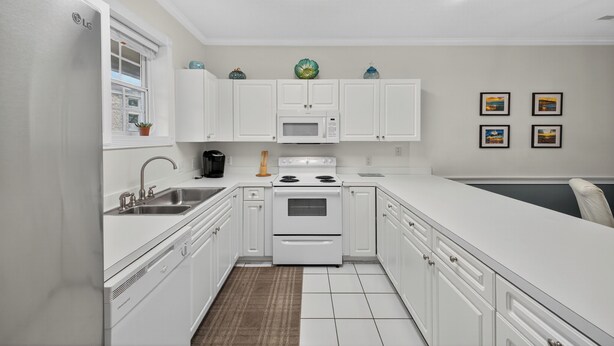 A modern kitchen with white cabinetry, a built-in microwave, and a stove. - Magnolia Place 4793-103 (Myrtle Beach)
