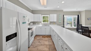 A modern kitchen with white cabinetry, a large island, and a window providing natural light. - Magnolia North 4827-201 (Myrtle Beach)