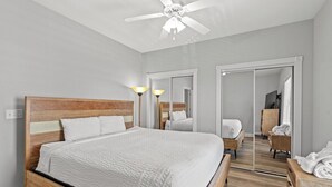 A bedroom with a wooden bed, a ceiling fan, a mirror, and a wooden nightstand. - Magnolia Pointe Magnolia Lake 4817-204 (Myrtle Beach)