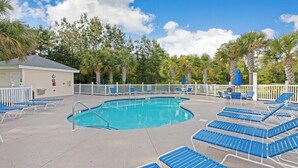 A pool area with blue lounge chairs and a small building with a sign. - Magnolia Pointe Magnolia Lake 4817-204 (Myrtle Beach)