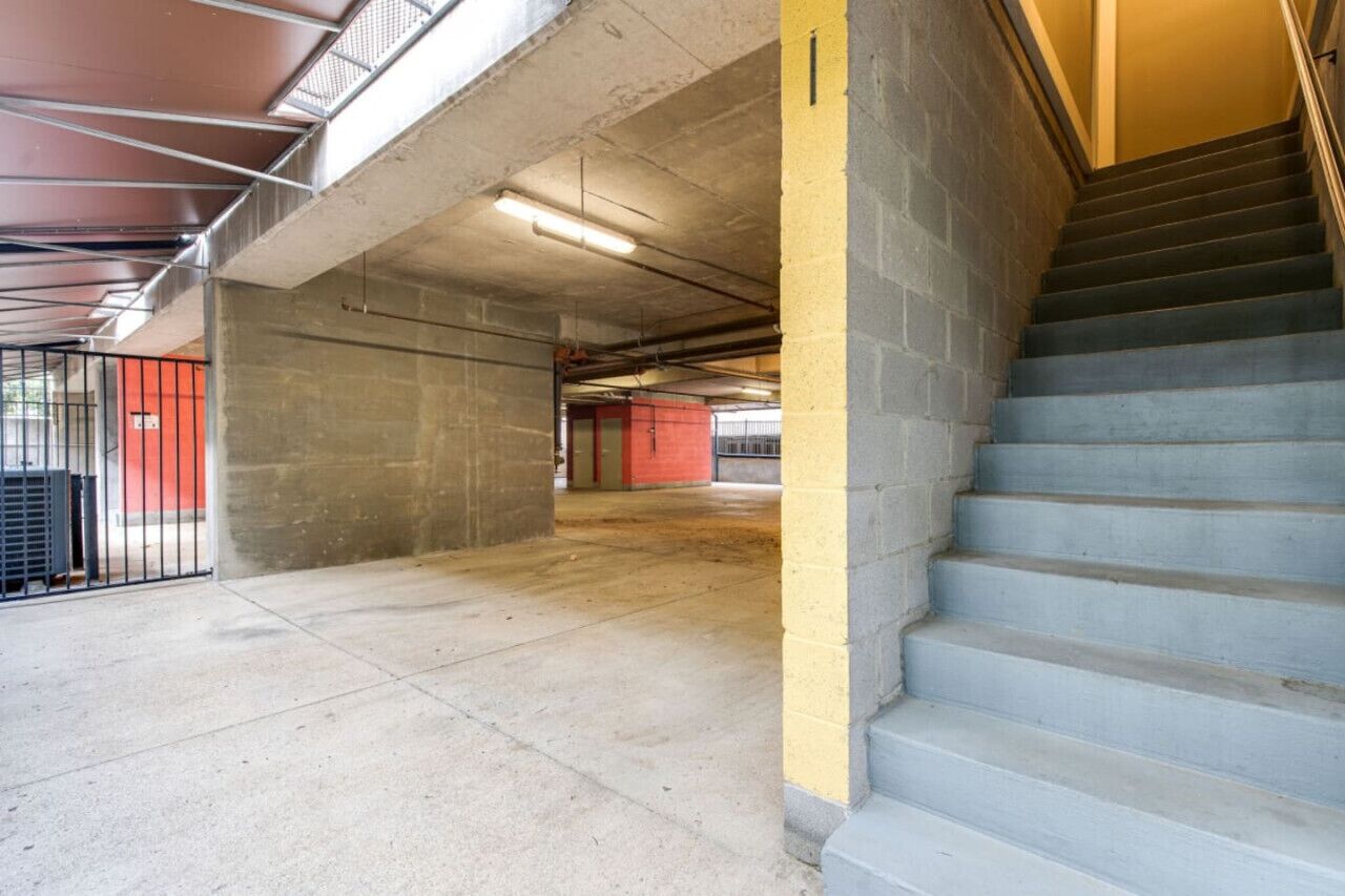 Een parkeergarage met meerdere verdiepingen, betonnen vloeren, een trap en een metalen poort.