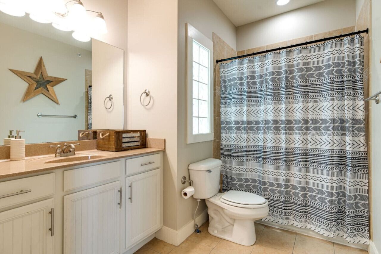 A bathroom with a white sink, a toilet, and a shower curtain with a geometric pattern.
