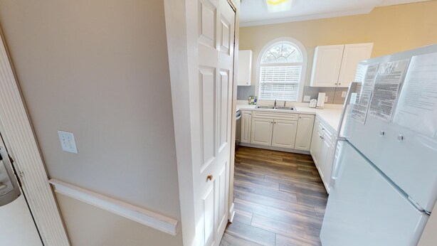 A kitchen with white cabinets, a stainless steel sink, and a refrigerator. - Magnolia Place 4687-302 (Myrtle Beach)