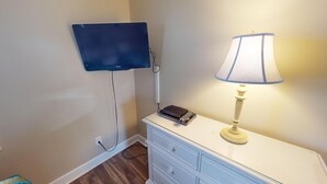 A room with a flat-screen TV mounted on the wall, a lamp on a dresser, and a power outlet on the wall. - Magnolia Place 4687-302 (Myrtle Beach)