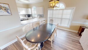 A spacious kitchen with white cabinets, a dining table, and a large window with blinds. - Magnolia Place 4687-302 (Myrtle Beach)