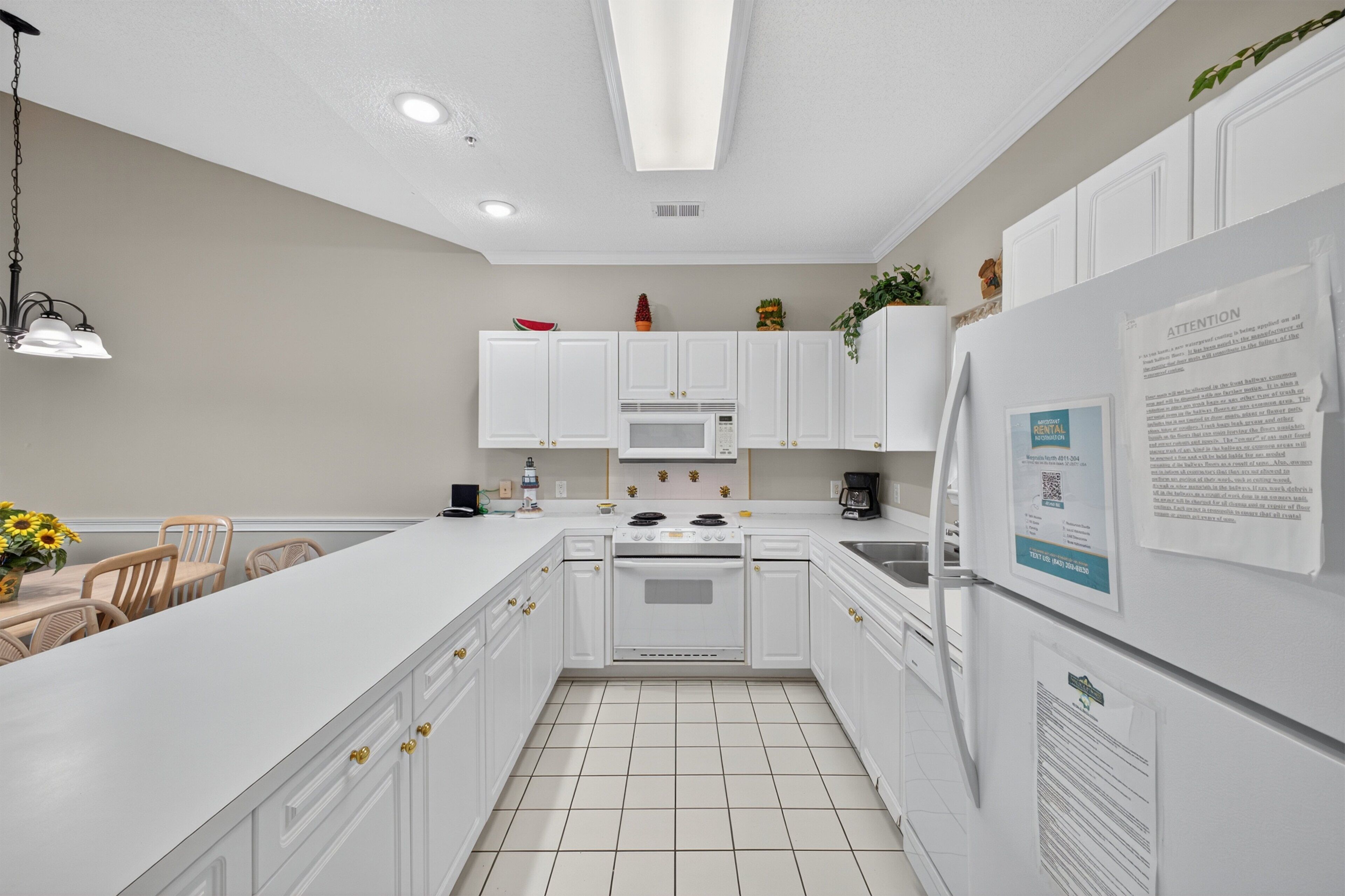 A modern kitchen with white cabinetry, a central island, a microwave, stove, and a refrigerator.