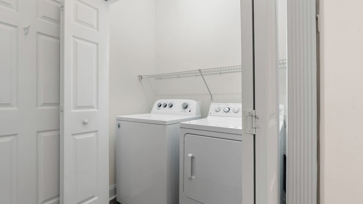 A laundry room with two white washing machines and a drying rack.