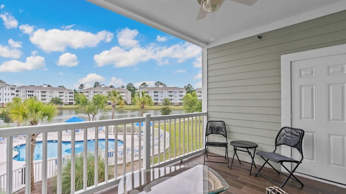 Un balcon donnant sur une piscine, une porte et deux chaises.