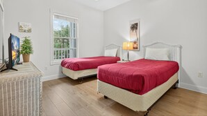 Camera da letto con due letti, una ventola a soffitto, una finestra e un televisore.