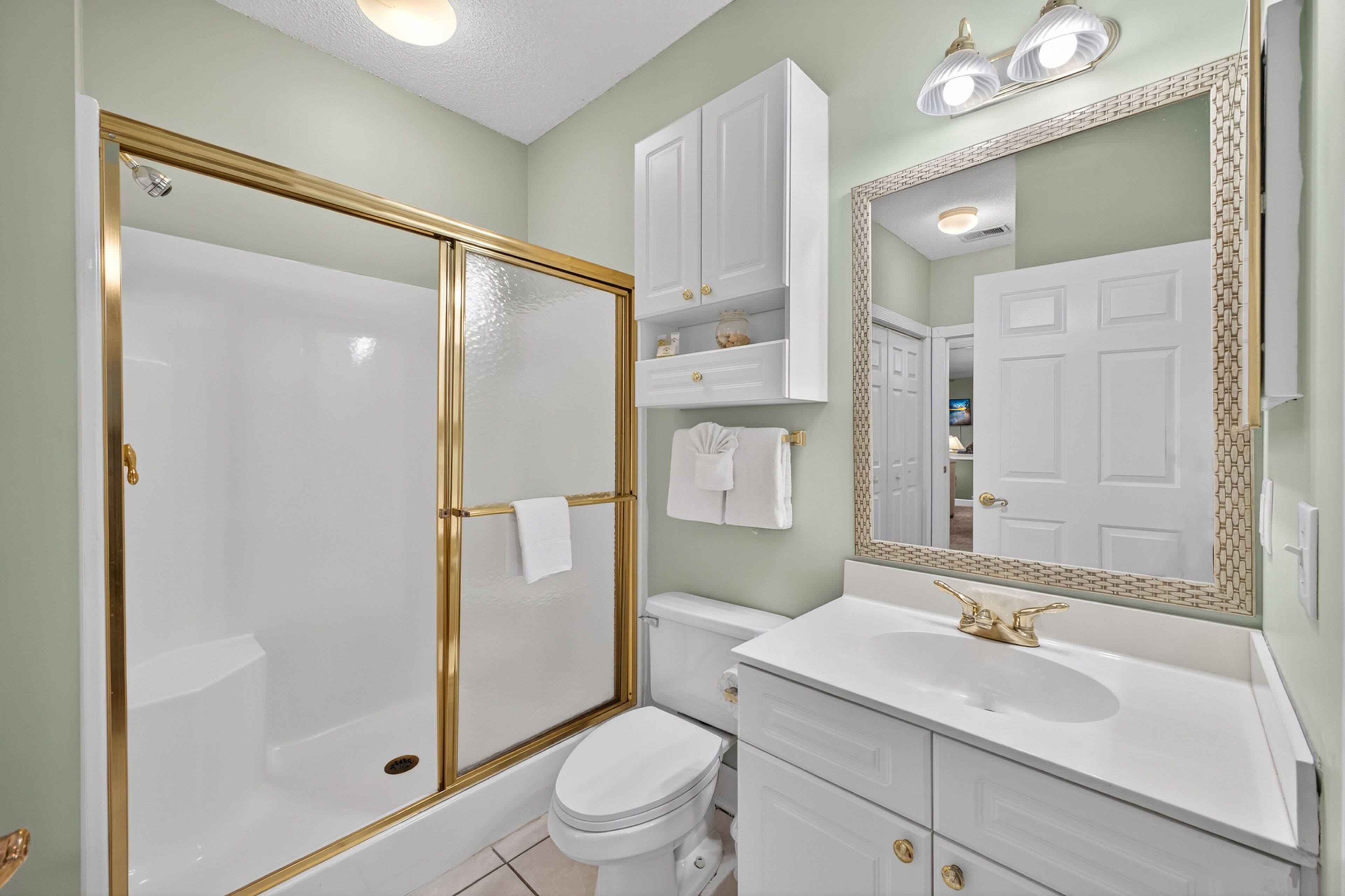 A bathroom with a walk-in shower, toilet, sink, and vanity.