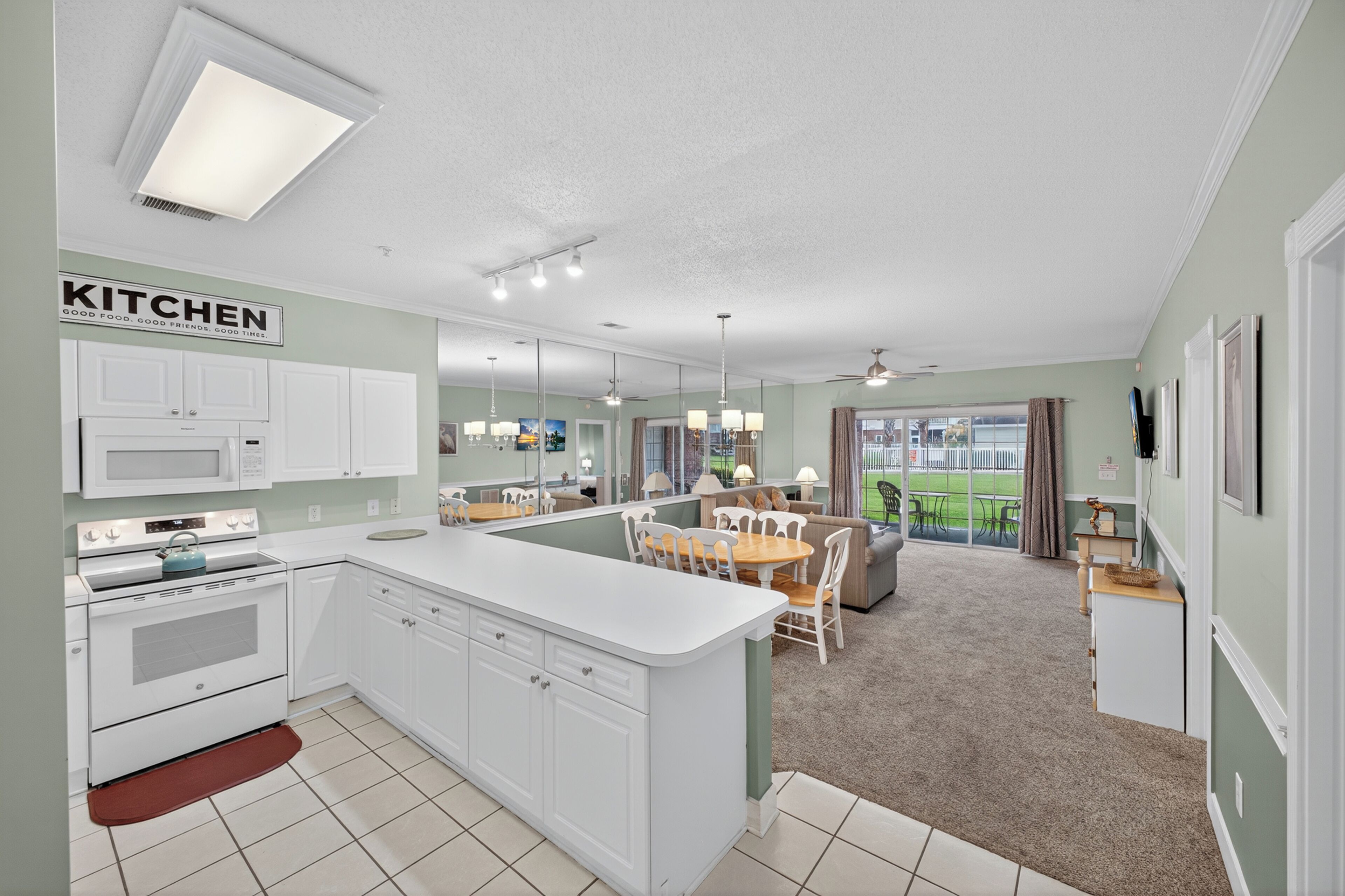 A modern kitchen with white cabinets, a central island, and a dining area with a table and chairs.