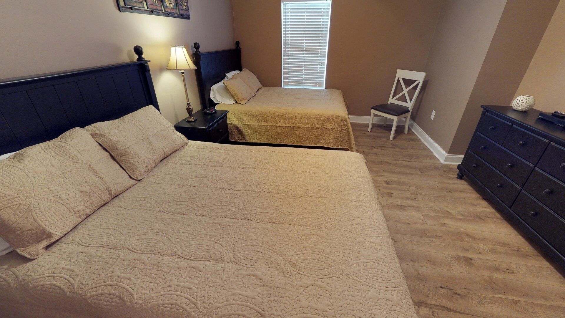 A bedroom with two beds, a nightstand, a chair, and a dresser.