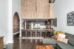 A modern kitchen with a central island, bar stools, and a dining area with a sofa and coffee table. - Bettye - A (Nashville)