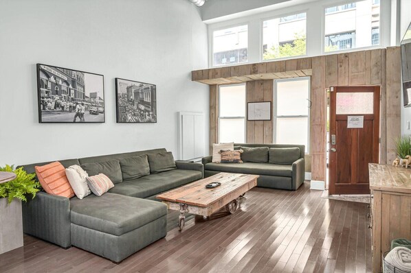 Un salón espacioso con un sofá modular, una mesita de centro y dos fotografías en blanco y negro enmarcadas en la pared.