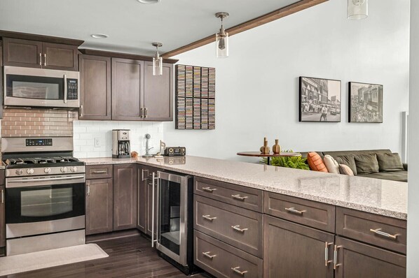 A modern kitchen with dark wood cabinets, stainless steel appliances, a granite countertop, and a built-in dishwasher. - Bettye - A (Nashville)