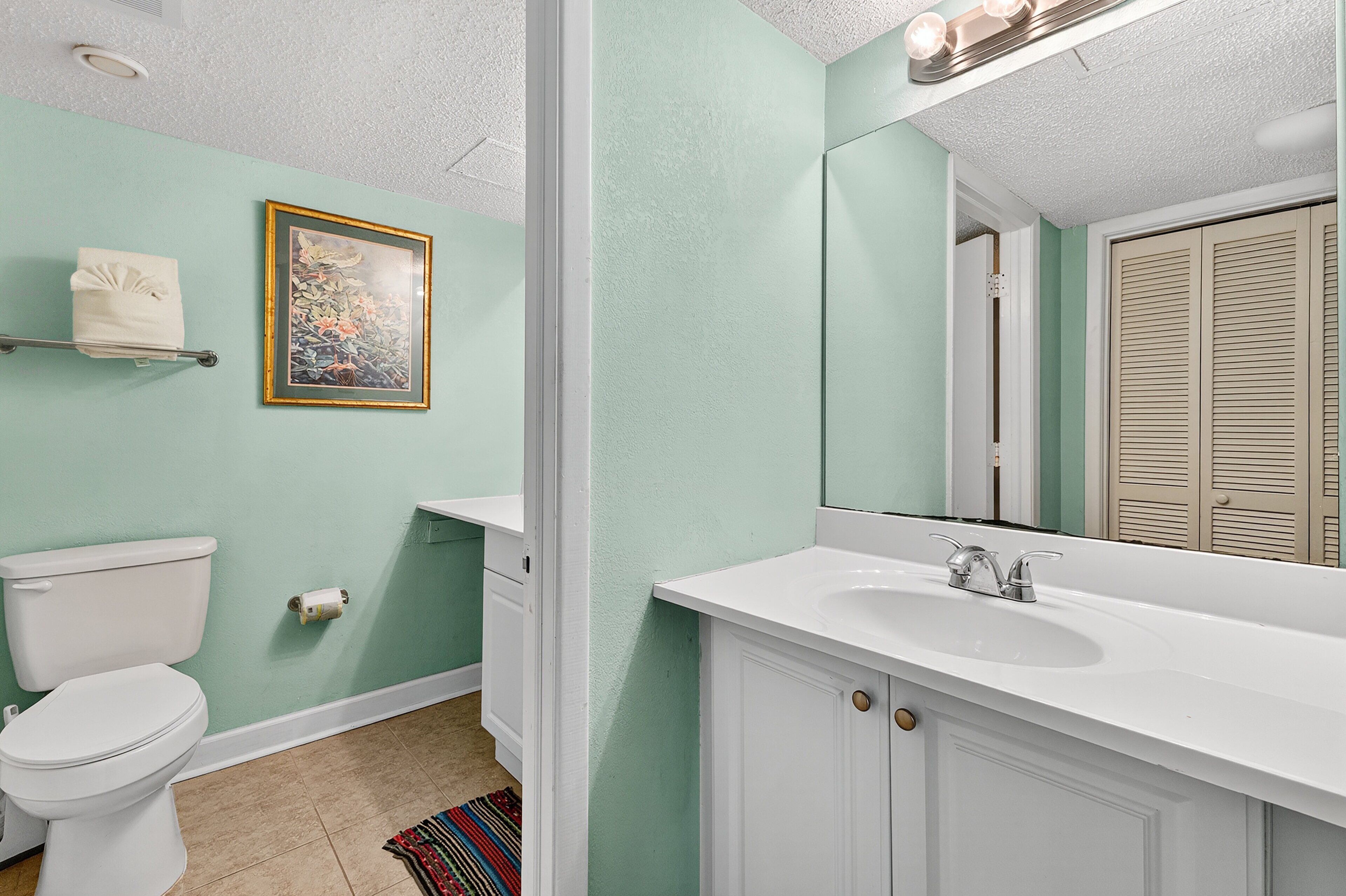 A bathroom with a toilet, sink, and mirror.