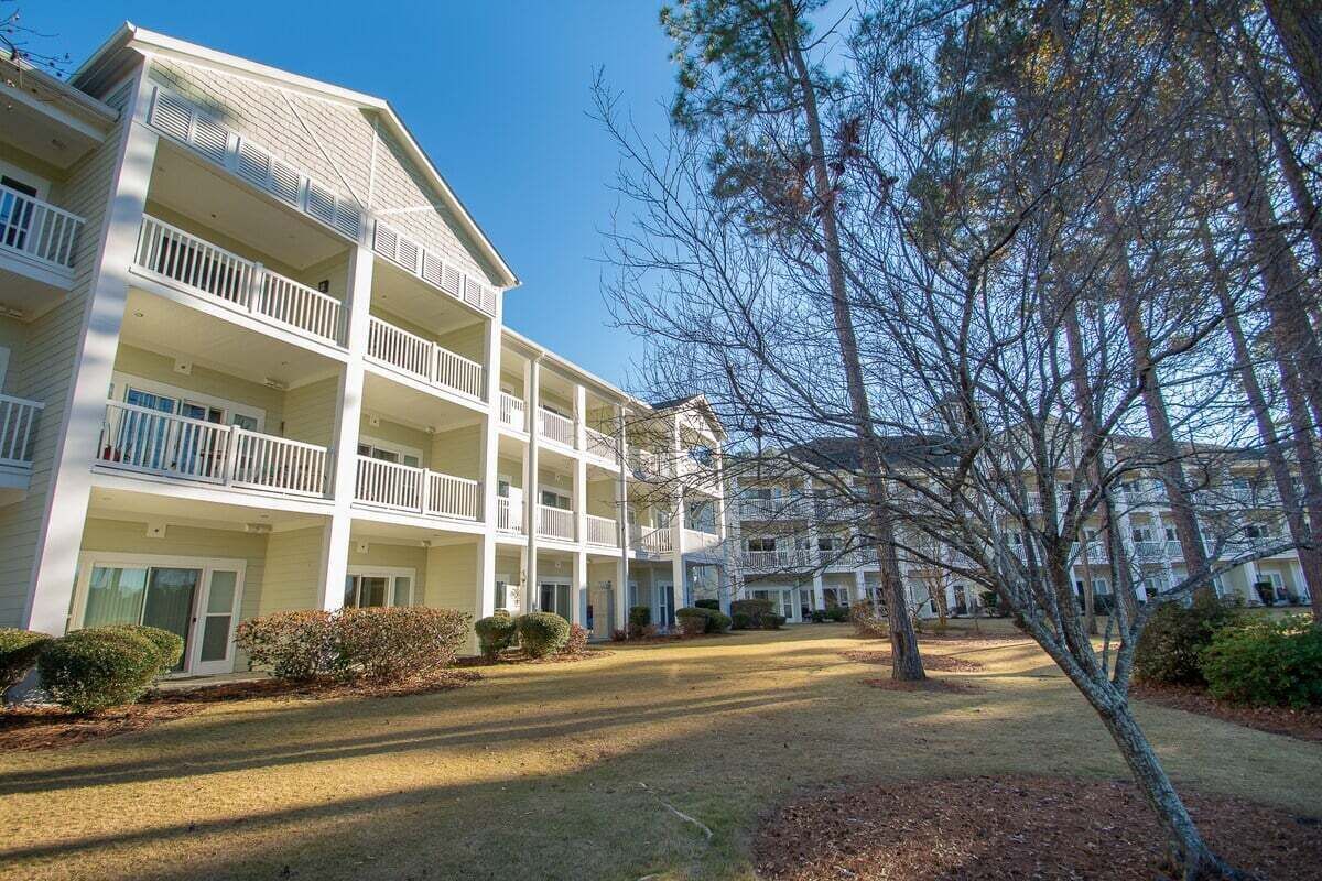 A multi-story hotel with balconies, a central courtyard, and surrounding trees.