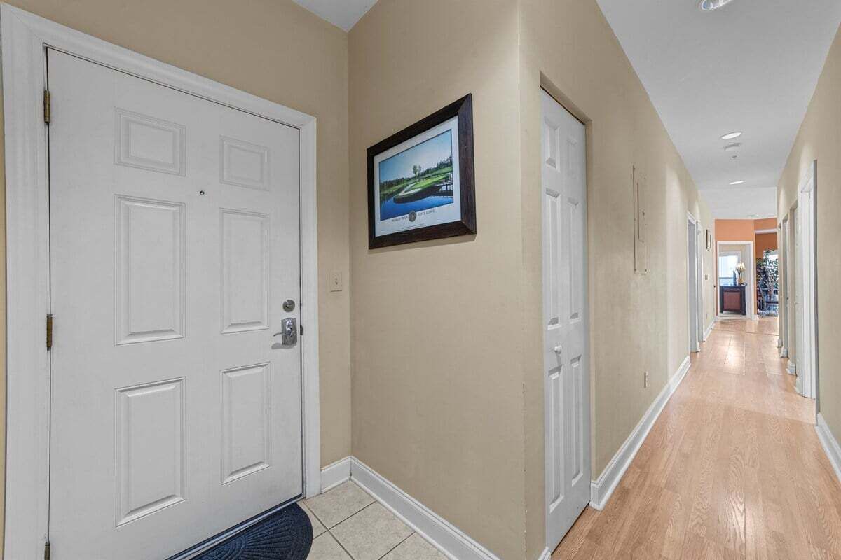 A hallway with beige walls, white doors, and a framed picture on the wall.