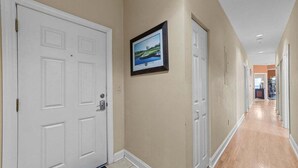 A hallway with beige walls, white doors, and a framed picture on the wall. - World Tour 104-206a (Myrtle Beach)