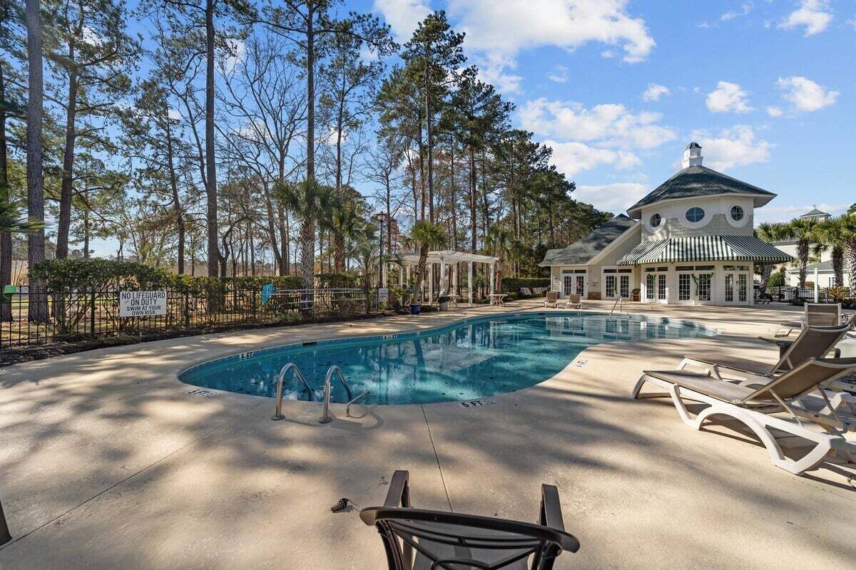 A swimming pool with lounge chairs, a gazebo, and a large building with a dome roof.