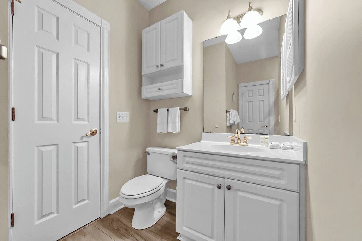 A bathroom with a white toilet, vanity, and a mirror.