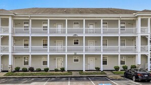 A two-story motel with a central entrance and a parking lot in front. - Magnolia Place 4665-104 (Myrtle Beach)