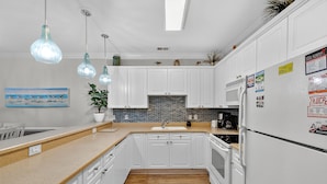 A modern kitchen with white cabinets, a wooden countertop, a backsplash, and a refrigerator. - Magnolia Pointe Luster Leaf 4882-104 (Myrtle Beach)