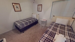 Ein kleines Schlafzimmer mit zwei Betten, einem Nachttisch und zwei gerahmten Bildern an der Wand.
