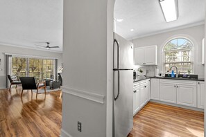 A spacious kitchen with white cabinets, a stainless steel refrigerator, and a large window. - Magnolia Place 4639-104 (Myrtle Beach)