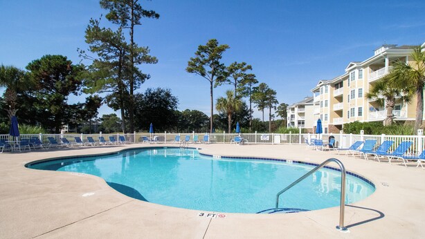 A swimming pool with a 3 ft depth marker, surrounded by lounge chairs and a white fence. - Magnolia North 4819-105 (Myrtle Beach)