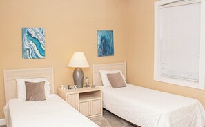A hotel room with two single beds, a nightstand with a lamp, and artwork on the walls. - Magnolia Place 4665-301 (Myrtle Beach)