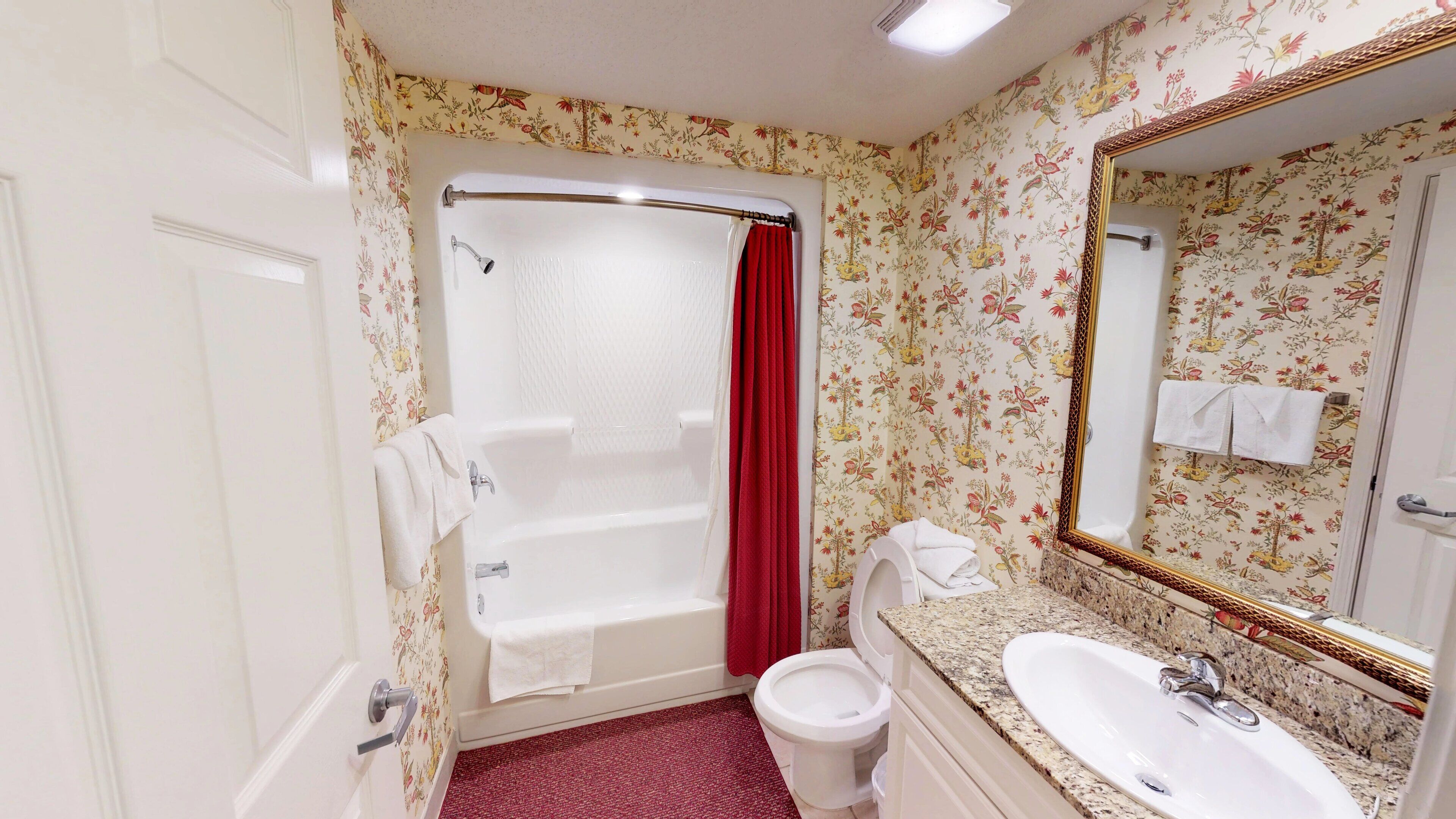 Une salle de bain avec une baignoire, des toilettes, un lavabo et un grand miroir.