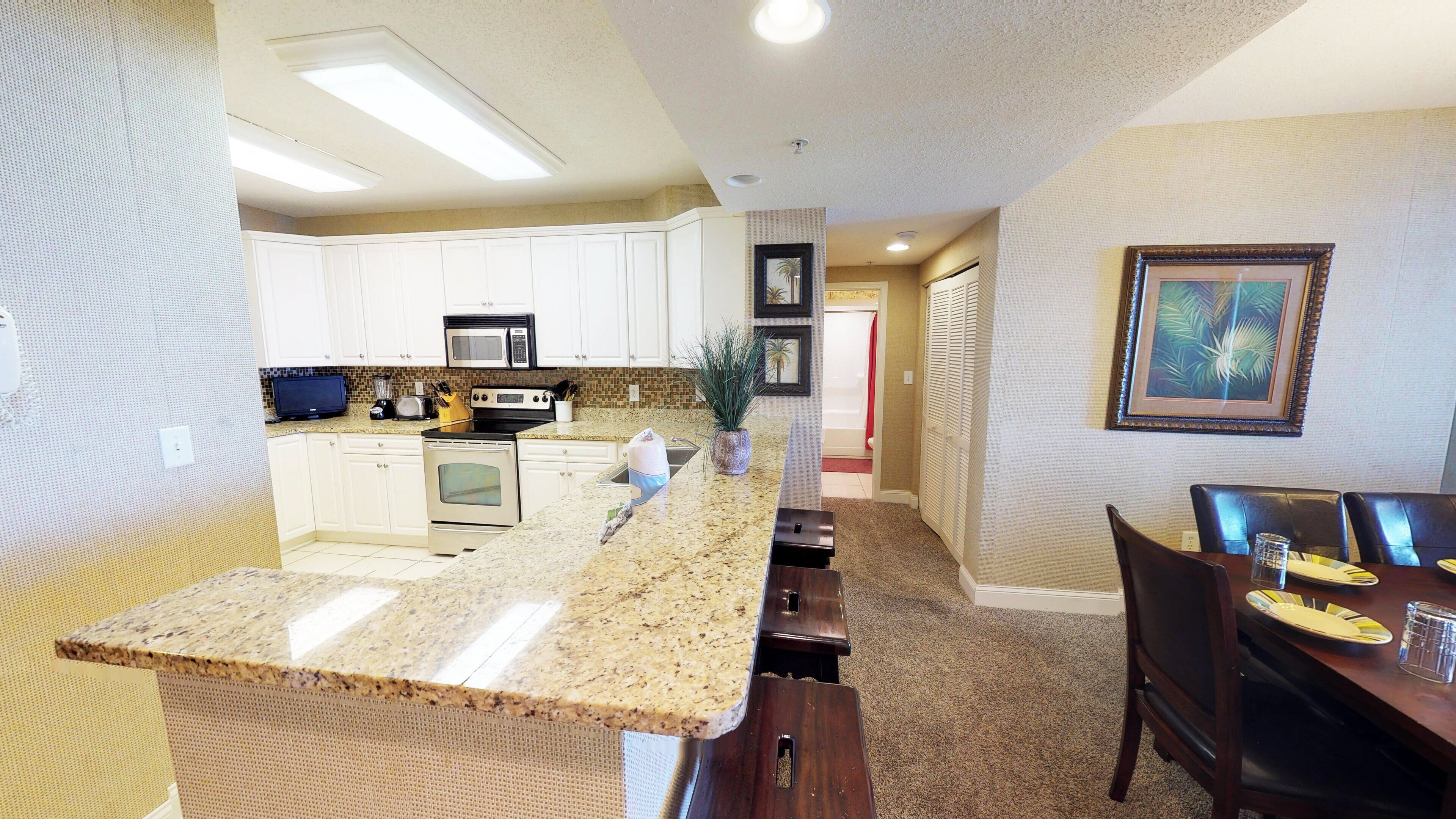 A modern kitchen with white cabinets, a granite countertop, and stainless steel appliances.