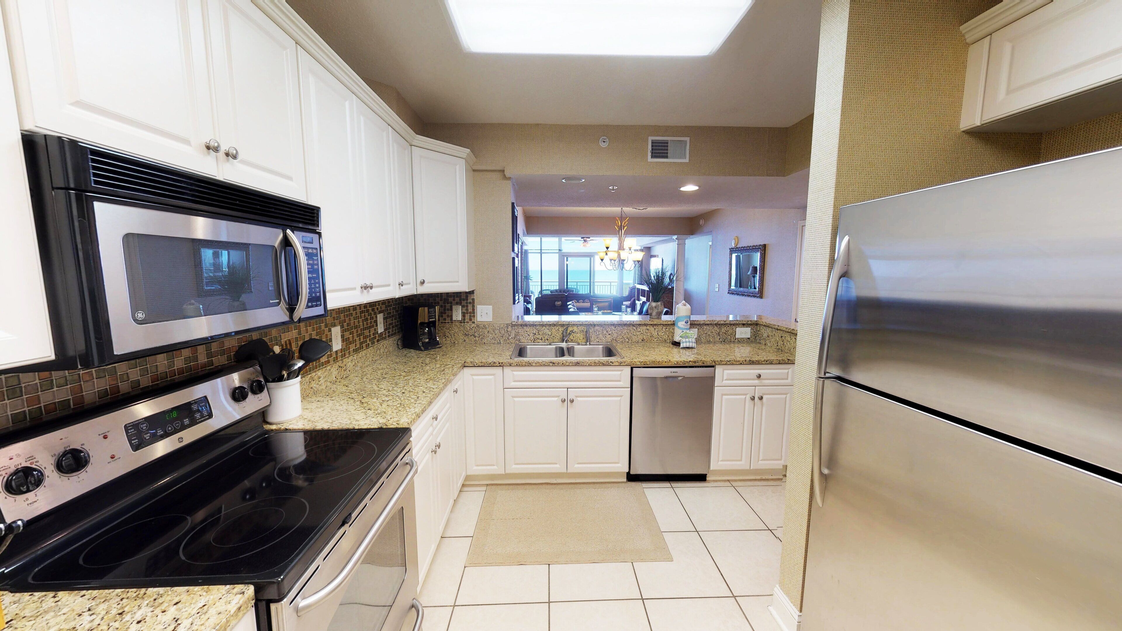 A modern kitchen with white cabinets, stainless steel appliances, and a tiled backsplash.