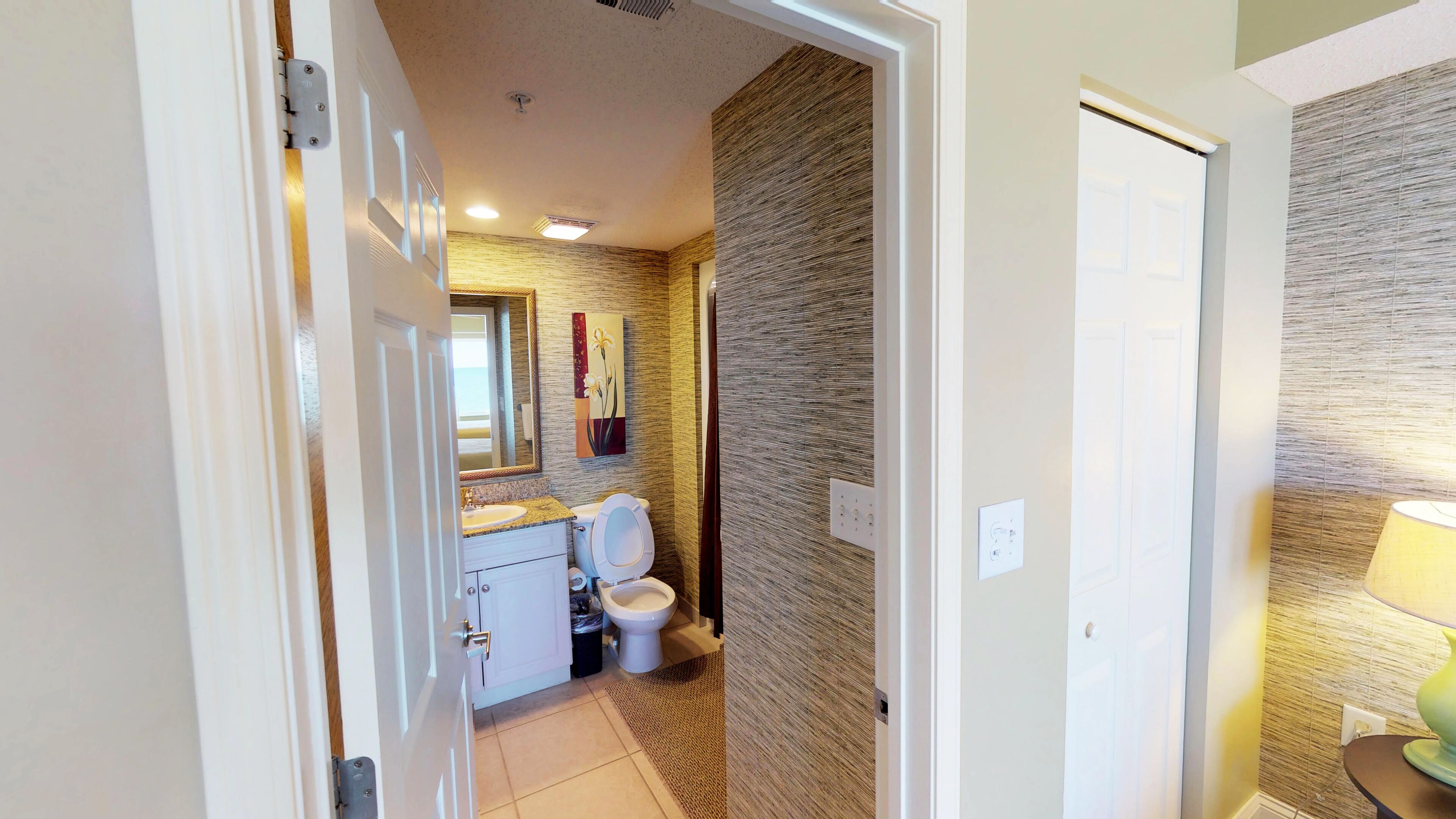 A bathroom with a toilet, sink, and mirror.