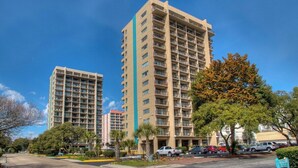 A high-rise hotel with multiple balconies and a parking area in front. - Ocean Dunes 6011 (Myrtle Beach)