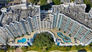 A high-rise hotel with multiple balconies, a central courtyard, and a swimming pool. - Horizon 701 (Myrtle Beach)
