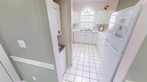 A kitchen with white cabinets, a window with blinds, and a tiled floor. - Magnolia Place 4639-301 (Myrtle Beach)