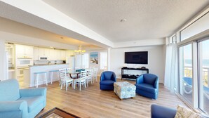 A spacious living area with a kitchen, dining area, and a balcony with a view. - Ocean Blue 401 (Myrtle Beach)
