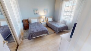 Ein Schlafzimmer mit zwei Betten, einem Nachttisch mit Lampe, einer Kommode und einem Bild an der Wand.