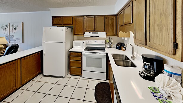A compact kitchen with a refrigerator, microwave, stove, and sink. - A Place at the Beach IV G143 (Myrtle Beach)