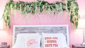 A bedroom with a pink wall, a wooden headboard, two pillows with text, a clock, and a bedside lamp. - Pink Party Nashville-near Music Row, Free Parking (Nashville)