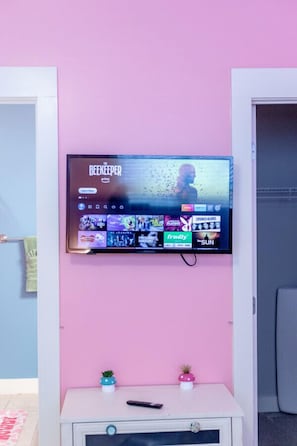 A television mounted on a pink wall displaying a streaming service interface with various game options. - Pink Party Nashville-near Music Row, Free Parking (Nashville)