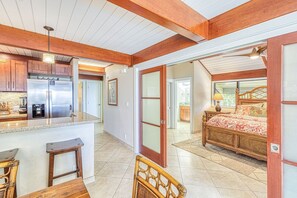A spacious kitchen with a refrigerator, coffee maker, and wooden bar stools. - Kahana Outrigger 4B1 (Napili-Honokowai)