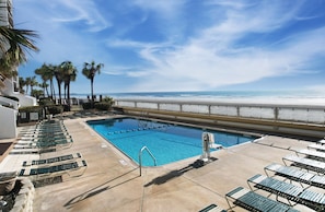 A pool area with lounge chairs, a clear blue pool, and a view of the beach. - Brigadune 12F (Myrtle Beach)