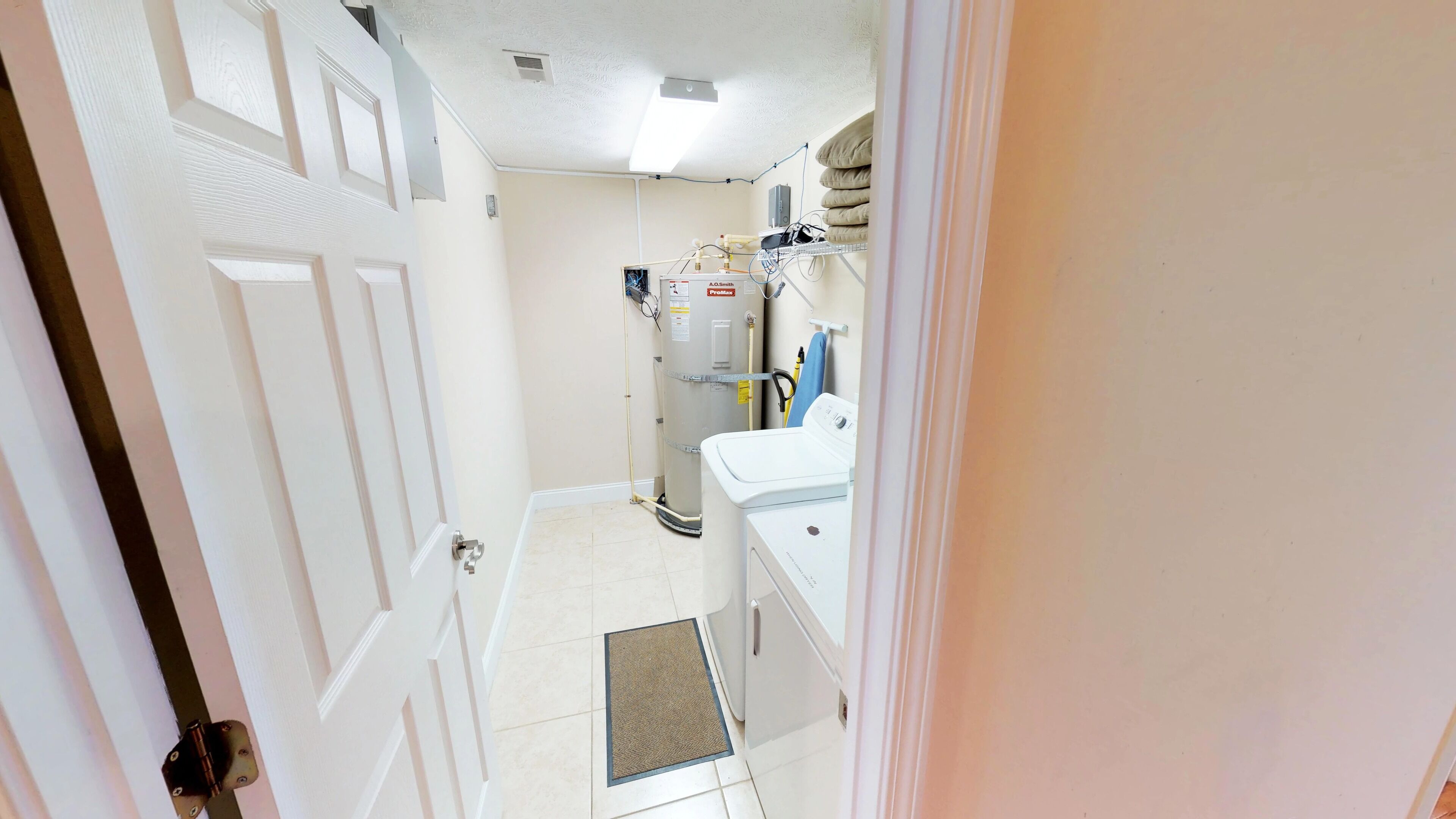 A narrow hallway with a white door, a washing machine, and a water heater.